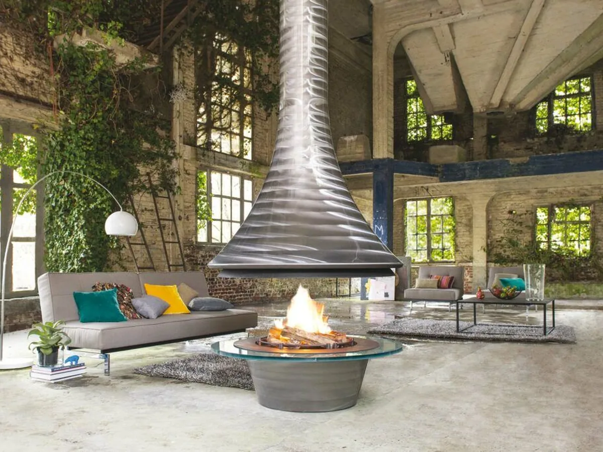 JC Bordelet suspended fireplace hanging in the center of an open loft with a sofa and tall windows