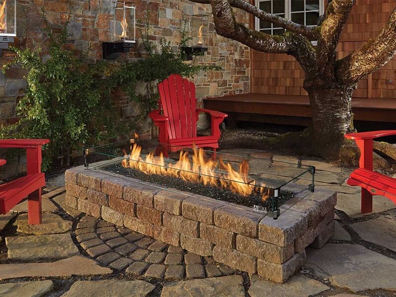 Wood-burning fire pit ringed by Adirondack chairs on a patio