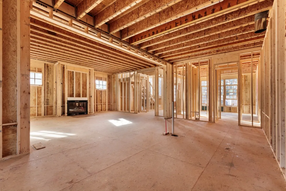 New-construction interior with exposed wood framing and a fireplace rough-in visible against the far wall
